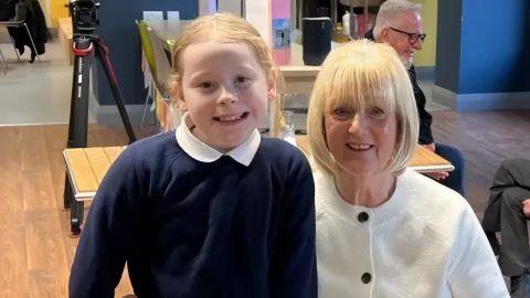 A young girl sat with a woman.