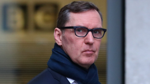 Alan Milburn seen outside the ̳ in London in 2017. He is wearing a pair of dark glasses and has a blue wool scarf wrapped around his neck.