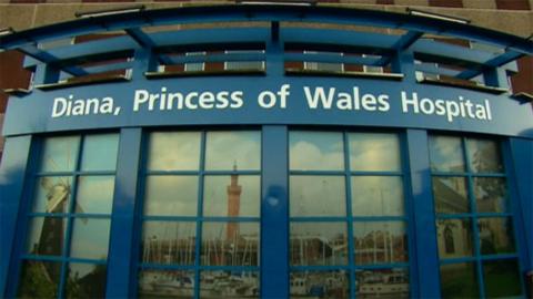 The main entrance to Diana, Princess of Wales Hospital in Grimsby. It is a blue curved, glass structure with images of local landmarks in the panes.