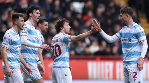 Wrexham players George Thomason (left), Kieffer Moore (second left), Ollie Rathbone (centre) and Callum Doyle (right) celebrate