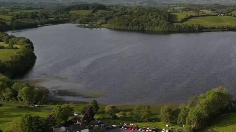 A lake surrounded by green fields and trees