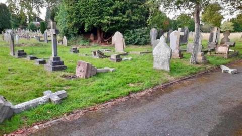 The broken gravestones lying on the grass in a graveyard