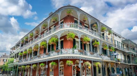 NOLA architecture, brick wall building with balconies and intricate ironwork columns in a street of the French Quarter, New Orleans, Louisiana 