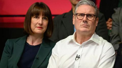 Chancellor Rachel Reeves wearing a dark green suit jacket, sitting alongside Prime Minister Sir Keir Starmer wearing a white shirt during the general election campaign