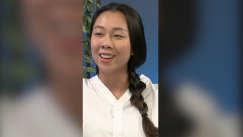 Journalist Mengchen Zhang speaks during the podcast. She has long black hair in a pigtail and wears a white top