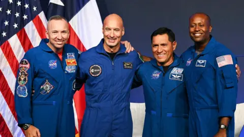 the artemis III astronauts stand with their arms around each other.