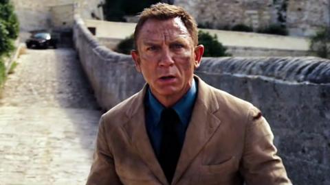 Actor Daniel Craig wears a brown suit and teal coloured shirt in a scene from No Time To Die.
