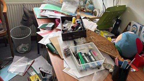 a desk with boxes and papers strewn over it