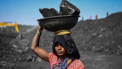 Workers carry coal at a coal yard near a mine on November 23, 2021 in Sonbhadra, Uttar Pradesh India. India is rapidly transitioning to renewables, investing in widespread solar and wind installations, though it still remains reliant on coal for about 70% of its energy needs, media reports said.