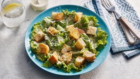 Caesar salad on a blue plate.