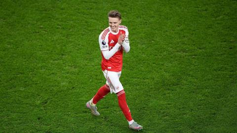 Martin Odegaard smiles as he applauds the Arsenal supporters
