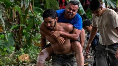 A Venezuelan migrant is helped by a friend as they arrive at the first border control of the Darién Province in Panama.