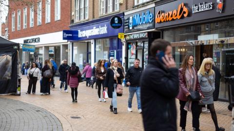 A scene of a high street in Chelmsford earlier this week shows people walking down the street and a man on his phone with shops lining the street.