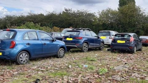 Cars parked on field littered with bricks