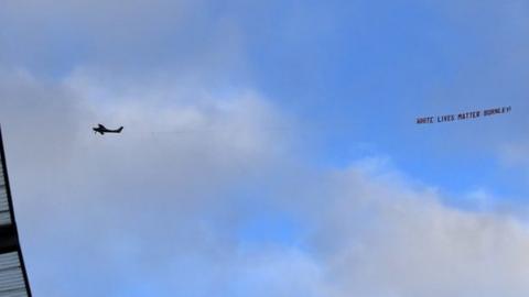 A banner reading 'White Lives Matter Burnley' is flown above Etihad Stadium before a Premier League match between Manchester City and Burnley