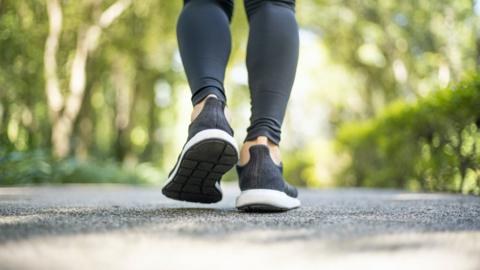 A close up of a woman's trainers as she walks down a path