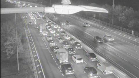A black and white image shows lots of vehicles in three or four lanes on a motorway