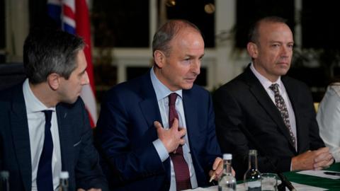 Taoiseach Simon Harris, Tanaiste Micheál Martin and Chris Heaton-Harris pictured in 2023's BIIGC. Micheál Martin is in the middle and is speaking to the crowd. 