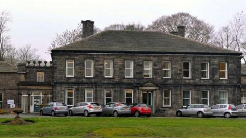Bingley Town Hall - a large, two storey brick building with six cars parked outside.