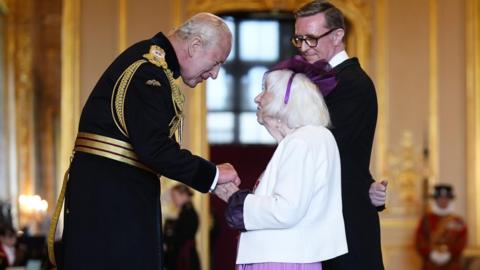 Betty Brown looking at King Charles III whilst holding his hand