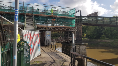 A bridge over muddy brown water with scaffolding over it.