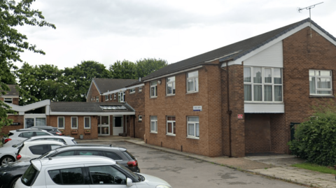 The front of the Hazel Garth building in Knottingley, with orange brick and white windows. 