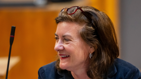 Eluned Morgan, smiling, in the Senedd debating chamber