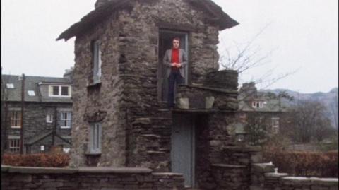 Man stands on upper floor of Ambleside Bridge House