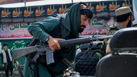 A Taliban fighter climbs up on a vehicle along a road in Kabul on 19 August 2021