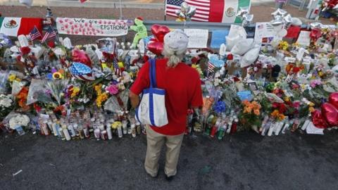 A woman stands over a memorial after a mass shooting in El Paso, Texas