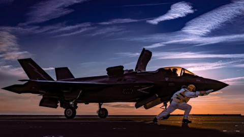 A lightning jet and pilot silhouetted against a sunset