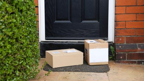 Two boxed parcels on a doorstep with a black door in the background