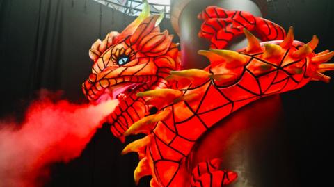 A bright red-and-orange model dragon with smoke billowing from its nostrils.