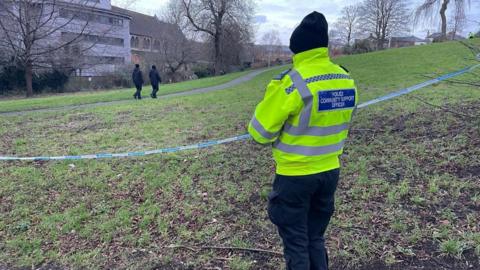 Police officer with their back to the camera standing next to a cordon at Victoria Park