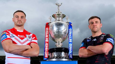 St Helens' Matty Lees and Wigan Warriors' Harry Smith stand alongside the Challenge Cup trophy
