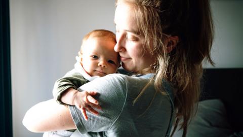A young mother holding a baby