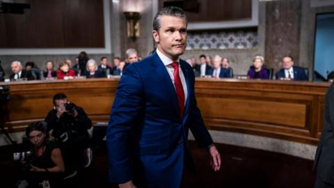 Pete Hegseth smirks while congressional committee sits in the background