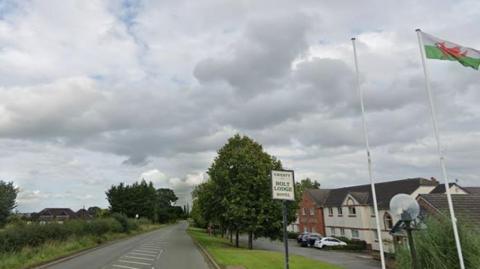 Google image of the road with the hotel to the right and flagpoles with Welsh flag at the entrance.