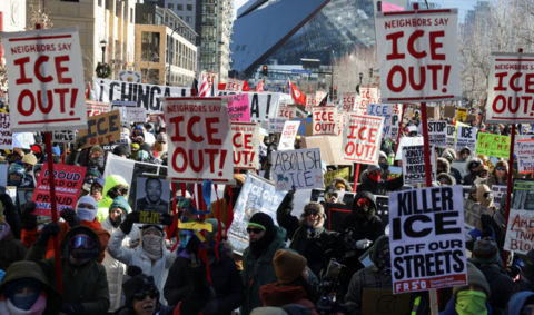 A number of anti-ICE protesters hold up signs during a demonstration 