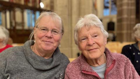 A mother and daughter smiling in the congregation of Leicester Cathedral