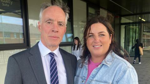 Roger Pollen and Shelley Teggart. Roger is wearing a suit and tie. Shelley is wearing a denim jacket and pink top.