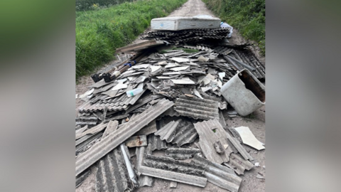 Dumped corrugated sheets with asbestos. They are filling a section of bridle path.