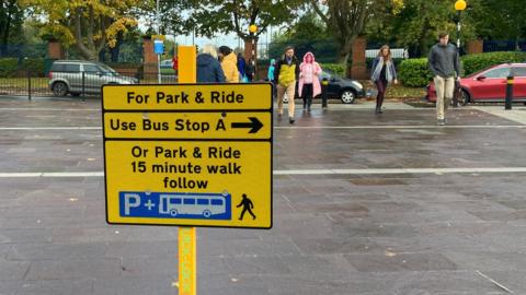 A sign at the entrance of the Royal Derby hospital points people towards a bus stop and the park-and-ride site itself