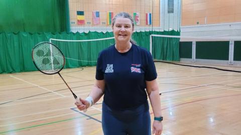 Lesley Miller holding a badminton racket and wearing her team Great Britain tracksuit.