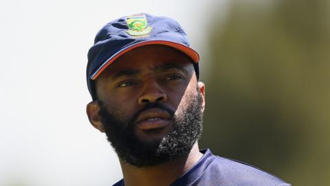 A headshot of Temba Bavuma with beard and wearing a navy blue cap with a South Africa Cricket emblem on it.