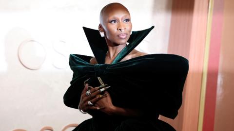 Cynthia Erivo poses during the Oscars arrivals at the 97th Academy Awards. Cynthia wears a green velvet off-the-shoulder dress.