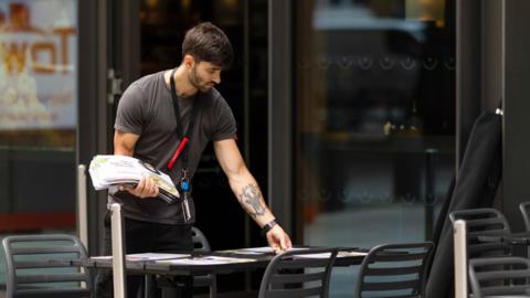 Man working as a waiter in a London cafe