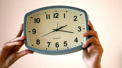 A woman holds a clock to change the time in Biot, southern France