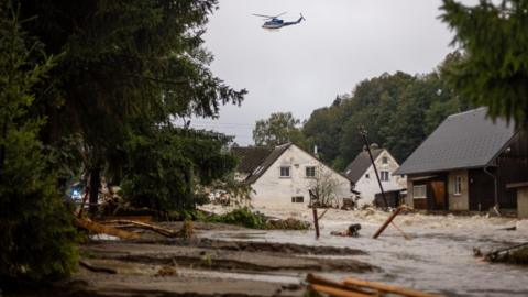 A police helicopter flies over overfloated houses in overfloating Bela river after heavy rain in town of Jesenik, Czech Republic