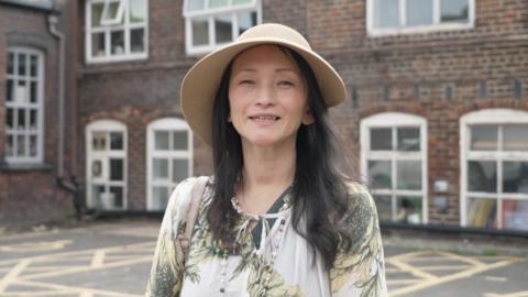 woman with straw hat facing camera smiling